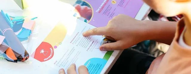 A kid carefully reading from an instruction booklet