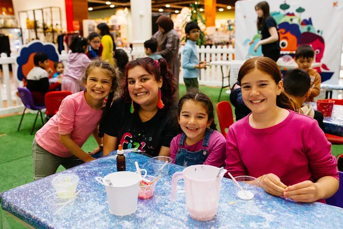 Kids in a shopping mall smiling with a Fizz Kidz staff member