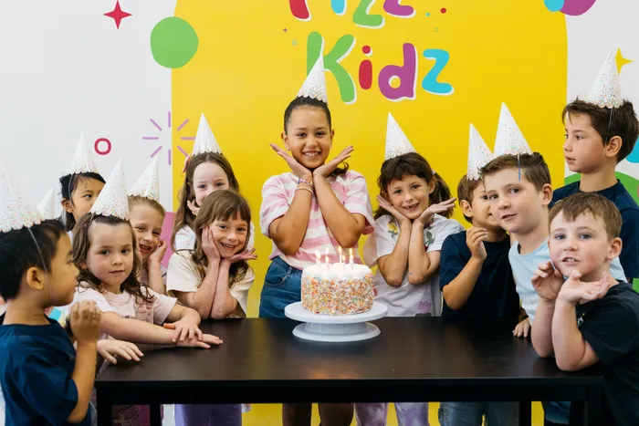 Kids smiling around a birthday cake