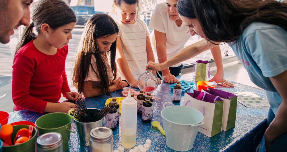 Fizz Kidz staff pouring soap into moulds as kids excitedly watch